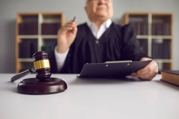 Senior rechter met pen en klembord zitten aan tafel shot met focus op hamer — Stockfoto