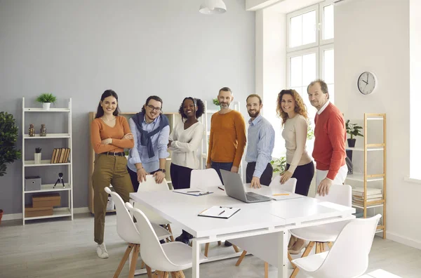 Портрет щасливої різноманітної ділової команди, що стоїть за офісним столом після корпоративної зустрічі — стокове фото
