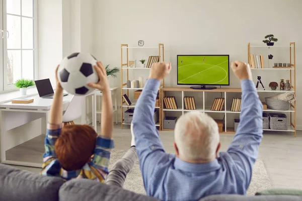 Morfar och sonson sitter på soffan, tittar på fotboll och stödja favoritlag — Stockfoto