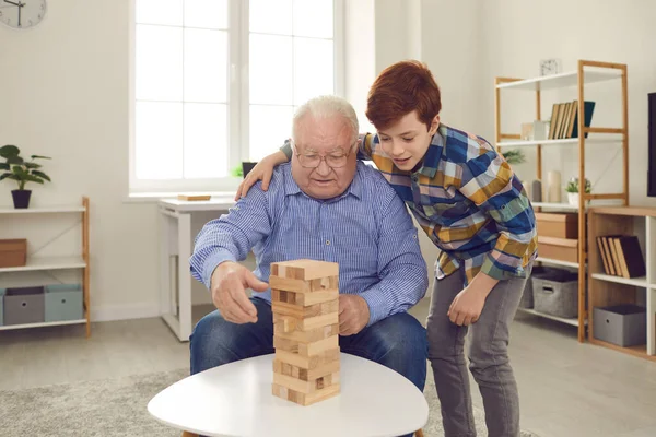 Nipote dando consigli al nonno su come rimuovere i blocchi di legno durante la riproduzione di gioco da tavolo — Foto Stock