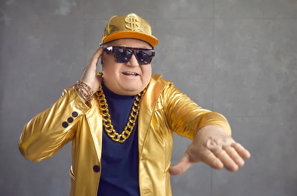 Divertente uomo anziano in giacca dorata, cappello da baseball e collana a catena che suona musica alla festa in discoteca — Foto Stock