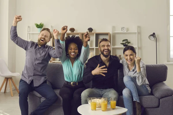 Multirassische Sportfans schreien, wenn die Mannschaft ein Tor schießt, während sie ein Fußballspiel im Fernsehen verfolgt — Stockfoto