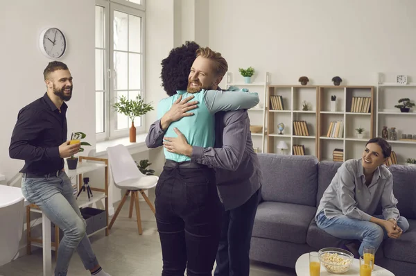 Mutlu genç insanlar birbirlerini kucaklıyor ve arkadaşlar partisinde buluşurken gülümsüyorlar.