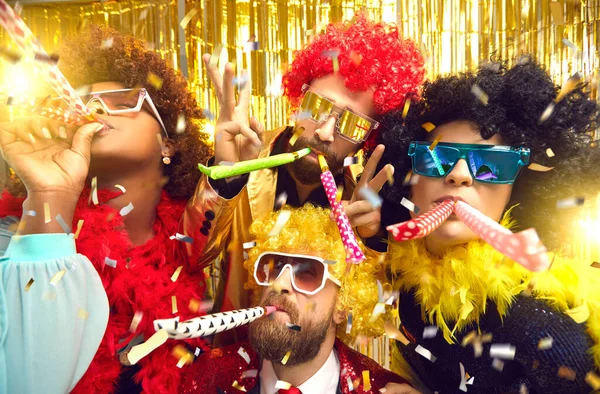 Empresa de amigos multiétnicos em desgaste de carnaval soprando em tubos de festa se divertindo — Fotografia de Stock