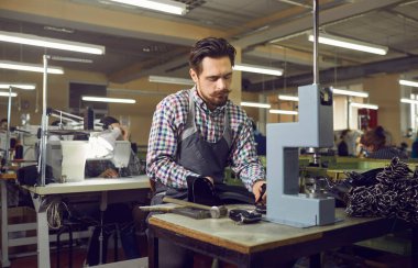 Genç beyaz erkek işçi ayakkabı imalat fabrikasında ayakkabı yapıyor.