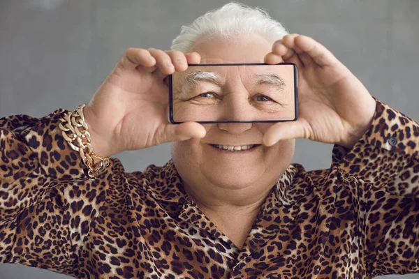 Divertente ricco paffuto uomo anziano in una camicia leopardata divertirsi con il suo telefono cellulare — Foto Stock