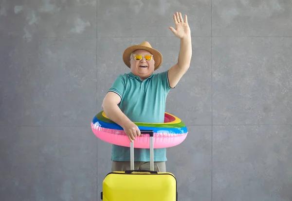 여행 가방을 들고 휴가를 떠나는 노인 관광객에게 즐거운 작별 인사와 손을 흔들며 — 스톡 사진