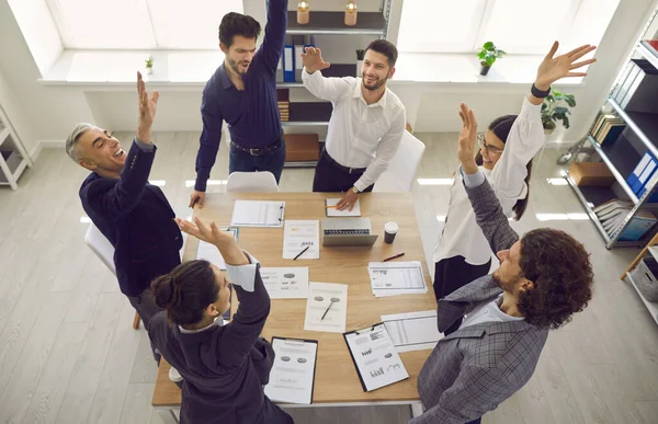 Equipe diversa entusiasmada celebrando o sucesso empresarial com as mãos levantadas — Fotografia de Stock
