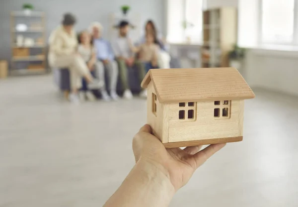 Nieruchomości konceptualne tło z ludzką ręką trzymającą mały dom rodzinny — Zdjęcie stockowe