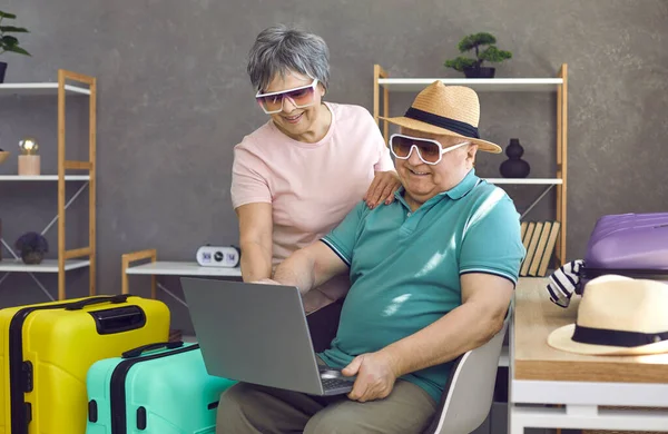 Drôle couple de personnes âgées en utilisant un ordinateur portable pour la recherche et la réservation de vacances de tournée — Photo