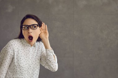 Şok olmuş bir kadın elini kulağına dayar ve konuşmaya kulak misafiri olur..