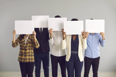 Yüzleri örten bir grup isimsiz insan beyaz maket kağıtlarının arkasına saklanıyor.