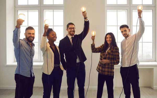Equipo de empresarios internacionales con bombillas elevadas que simbolizan la idea. — Foto de Stock