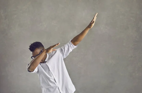 Young black man doing popular dab dance move isolated on gray concrete background — Stock Photo, Image