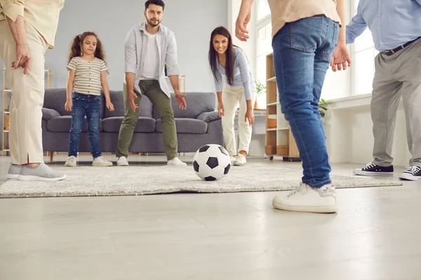 Happy mom, dad, grandparents and kids playing with soccer ball and having fun at home