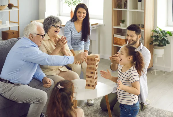 Uma família grande feliz todos juntos jogando o jogo de tabuleiro de torre de bloco de madeira em casa — Fotografia de Stock