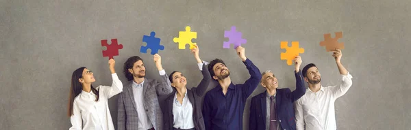 Team von glücklichen Geschäftsleuten, die in Reihe stehen und bunte Puzzleteile in der Hand halten — Stockfoto