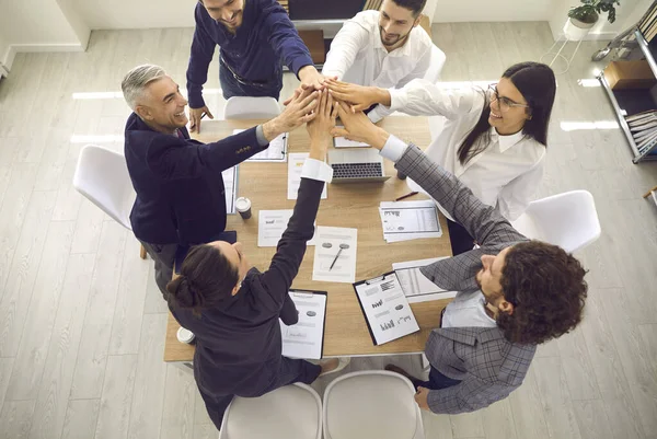 Equipe de vendas feliz em torno de uma mesa de escritório e dando um ao outro um alto cinco — Fotografia de Stock