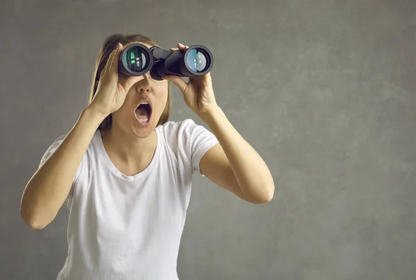 Mujer curiosa emocionada mirando a través de binoculares espiando y tratando de descubrir secretos. — Foto de Stock