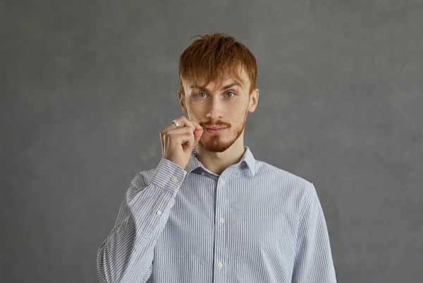 Casual homme aux cheveux roux montrant la bouche avec fermeture éclair signe secret studio tourné — Photo