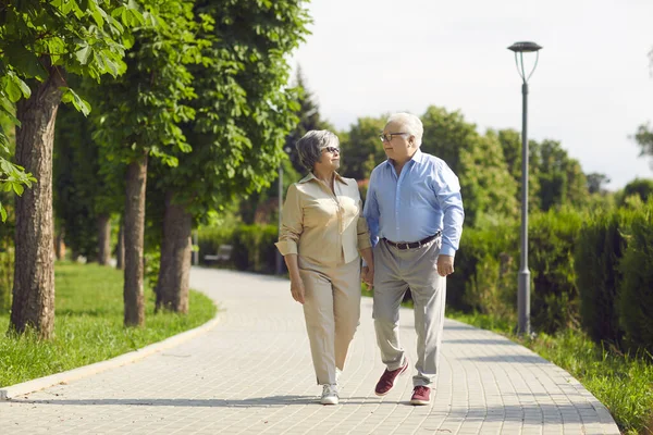 Alegre pareja de ancianos pasándola bien en un parque de la ciudad caminando, riendo y disfrutando de un día soleado. — Foto de Stock