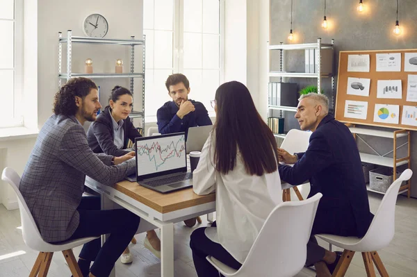 Obchodní tým diskutovat o svých plánech sedí kolem kancelářského stolu na firemní schůzi — Stock fotografie