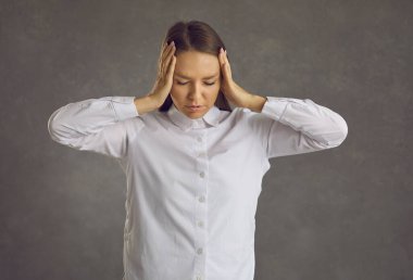 Kafası karışmış, gözleri kapalı genç bir kadın elleriyle başını iki taraftan tutuyor..