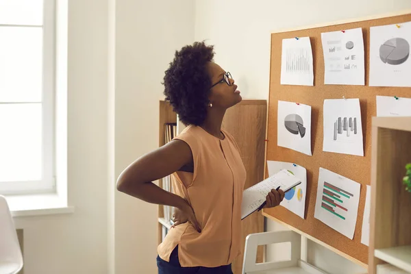 Jovem afro-americana empregada de pé perto do conselho com gráficos e gráficos — Fotografia de Stock