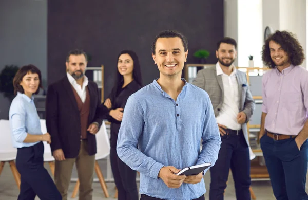 Portrét šťastného vedoucího obchodního týmu stojícího v úřadu se skupinou zaměstnanců — Stock fotografie