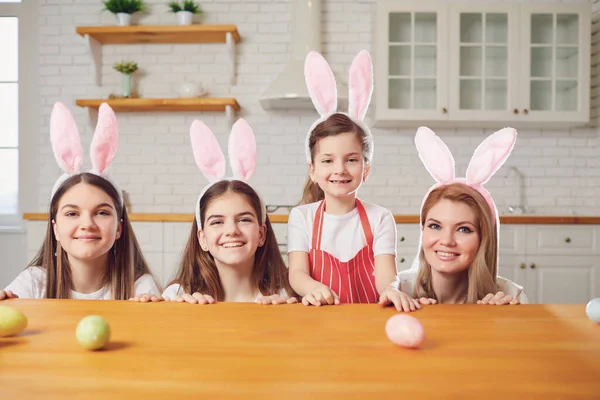 快乐的复活节。在厨房的桌子旁，母亲和女儿们用兔子耳朵装饰复活节彩蛋. — 图库照片