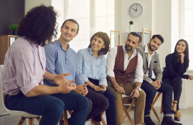 Bir grup mutlu iş adamı toplantı sırasında bir meslektaşını dinliyor.