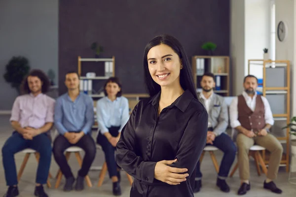 Portrait d'une jeune femme d'affaires heureuse debout devant une équipe de collègues ou d'employés — Photo