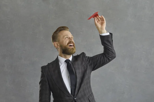 Retrato de un exitoso empresario caucásico a punto de dirigir un avión de papel sobre un fondo gris. — Foto de Stock