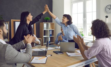 İki mutlu meslektaş ofiste beşlik çakıyor ve başarıyı kutluyor.