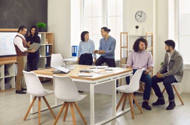 İş adamları ya da şirket çalışanları modern bir ofiste buluşup birlikte çalışıyorlar.