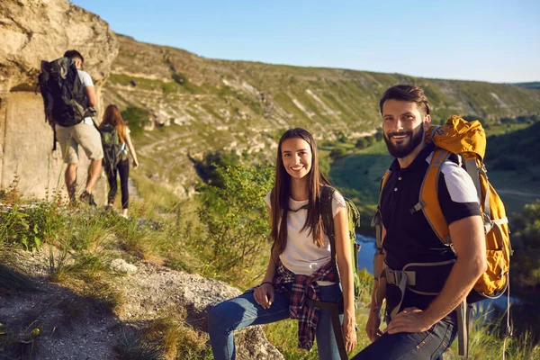 Portrét několika mladých turistů s batohy na pozadí skalnatých hor. — Stock fotografie