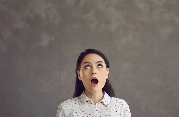 Young caucasian woman with opened mouth looking up feeling shock emotion — Stock Photo, Image