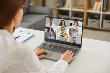 İnternette iş görüşmesi yapan bir kadın laptopuyla masada oturuyor.