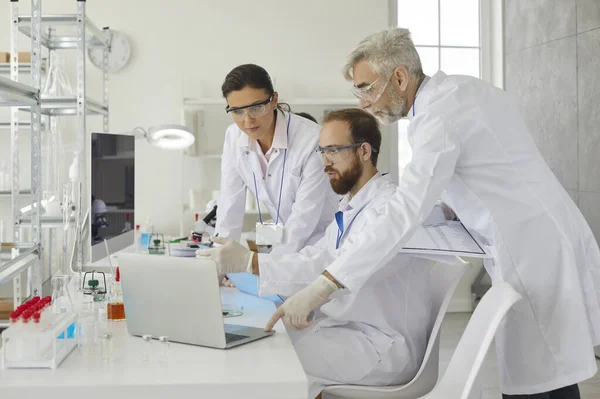 Grupo de pesquisadores discute a pesquisa com supervisor sênior do sexo masculino em laboratório. — Fotografia de Stock