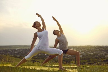 Formda erkek ve kadın, yaz aylarında birlikte yoga yapıyorlar.