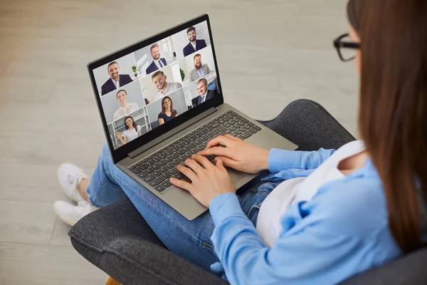 Жінка, яка проводить віртуальну ділову зустріч, сидить у кріслі зі своїм ноутбуком — стокове фото