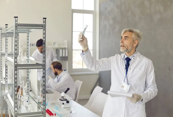 Serieuze senior mannelijke wetenschapper die werkt met chemische monsters in een modern wetenschapslab. — Stockfoto