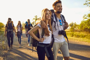 Bir çift kırsalda arkadaşlarıyla yürüyüş yapıyor. Mutlu gezginler yazın vahşi doğada gezerler.