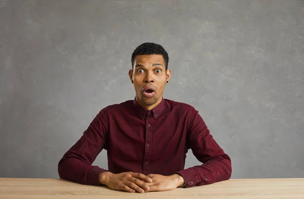 Dunkelhäutiger Mann mit überraschtem und schockiertem Gesichtsausdruck, betäubt von unerwarteten Nachrichten oder Informationen. — Stockfoto