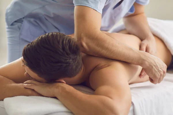 Homem desfrutando de massagem corporal feita por massagista profissional durante a terapia de reabilitação — Fotografia de Stock