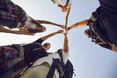 Tatillerde doğa yürüyüşü yapan genç turistlerin yıldız şeklinde el sıkışması.