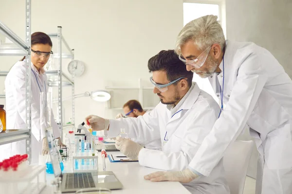 Grupo de cientistas que trabalham em laboratório, fazendo pesquisa e usando equipamentos de laboratório modernos — Fotografia de Stock