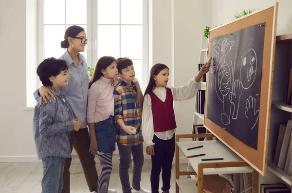 Elementary school girl student answering at board on lesson front of classmates — стоковое фото