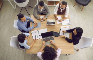 Ofis masasının etrafında toplanan profesyonel bir iş ekibinin görüntüsü.