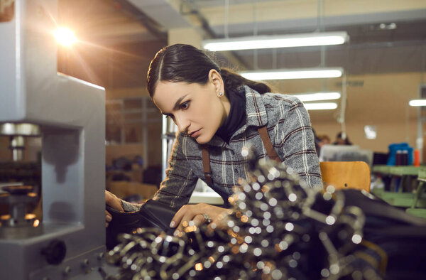 Female worker making new leather boots at manufacturing workshop at shoe factory